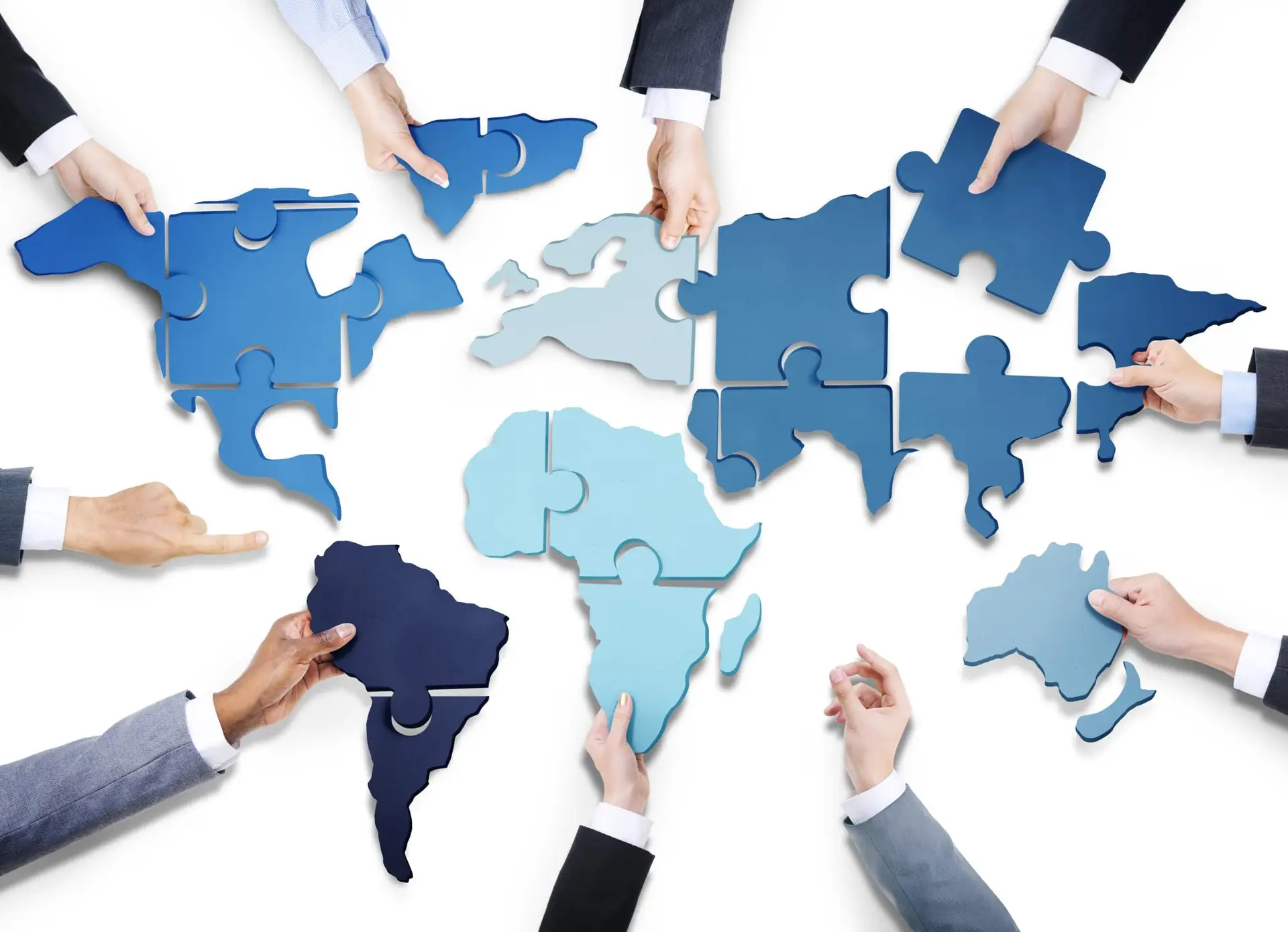 Hands assembling a world map puzzle